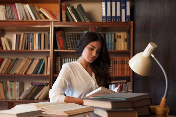 Menina sentada à mesa lendo um livro está se preparando para o exame — Fotografia de Stock