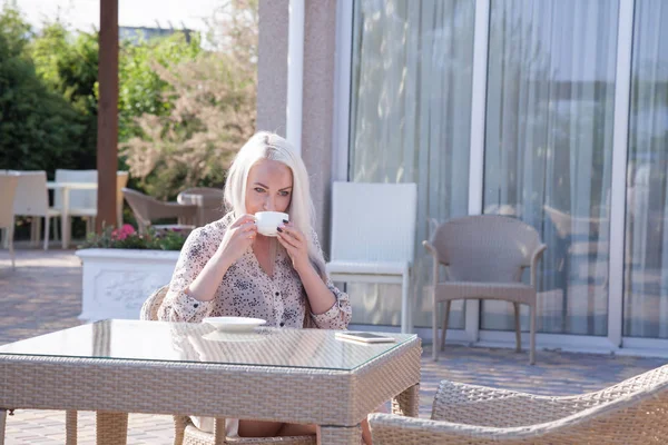 blonde girl sitting at the beach restaurant coffee