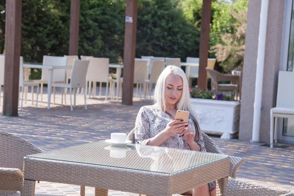 blonde girl sitting at the beach restaurant coffee