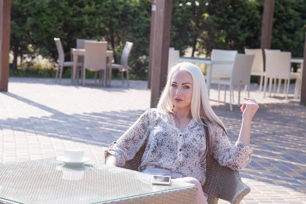 blonde girl sitting at the beach restaurant coffee