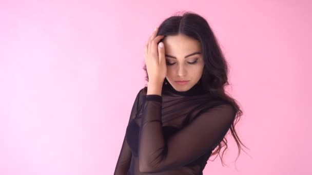 Брюнетка дівчина позує на рожевому фоні посмішка емоції — стокове відео