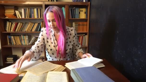 Flickan förbereder sig för examen i biblioteket läsa böcker — Stockvideo
