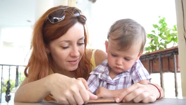 Een kleine jongen met moeder maakt gebruik van Internet op Smartphone — Stockvideo