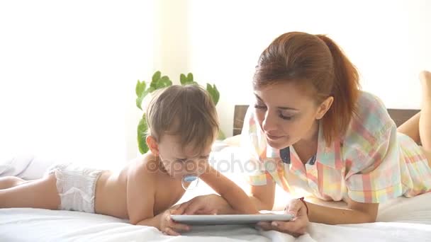 Мати і син молодих користувався планшетний в Інтернеті в спальні — стокове відео