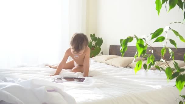 Petit fils se trouve sur le lit dans la chambre et regarde Internet Tablet — Video