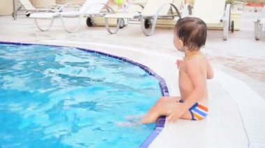 küçük oğlan poolside resort adlı oturuyor