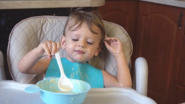 Menino come mingau de cereal para o café da manhã — Vídeo de Stock