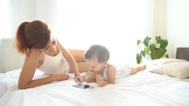 Anne ve bebek yatak odasında smartphone bak