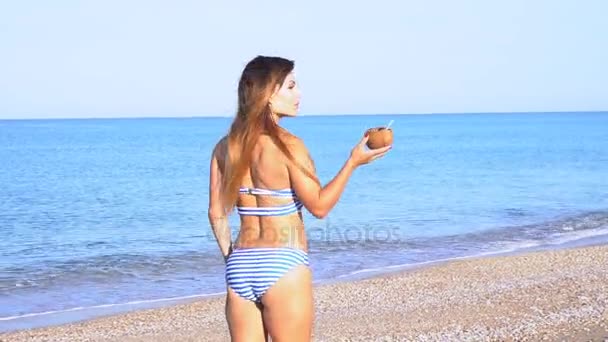 Krásná dívka s koktejl na pláži v letovisku nedaleko oceánu — Stock video
