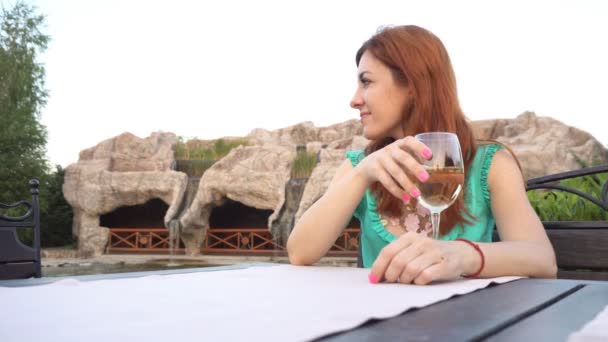 Дівчина в ресторані на вулиці п'є вино — стокове відео