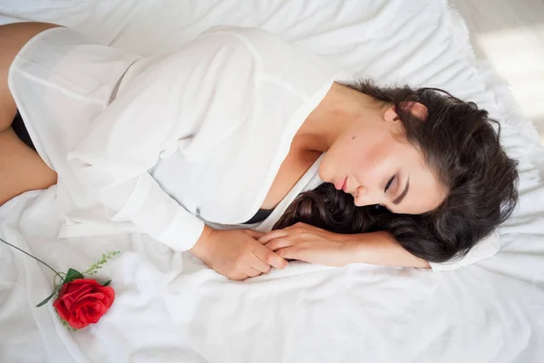 Menina em lingerie deitado em uma cama com uma rosa — Fotografia de Stock