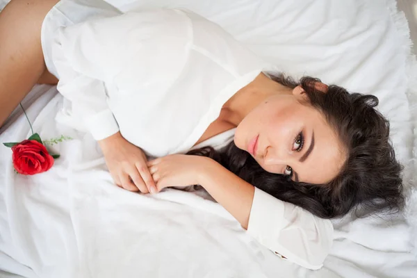 Chica en lencería acostada en una cama con una rosa —  Fotos de Stock