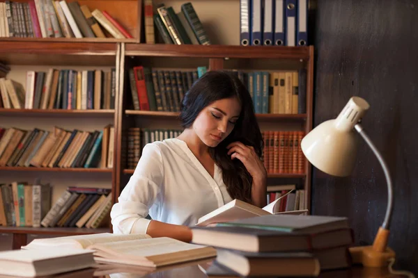 Chica sentada en la mesa leyendo un libro se está preparando para el examen — Foto de Stock