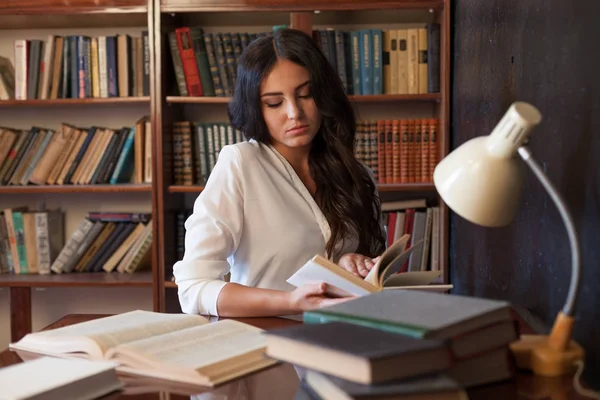 Chica sentada en la mesa leyendo un libro se está preparando para el examen — Foto de Stock