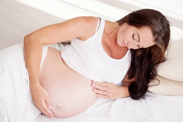 Une femme enceinte est couchée dans son lit en attendant la naissance d'un enfant — Photo