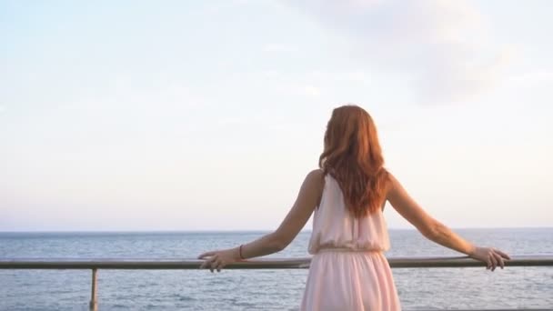 Девушка с рыжими волосами смотрит в океан — стоковое видео