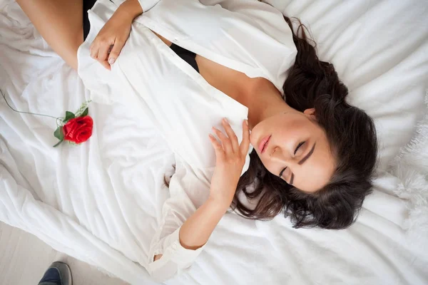 Chica en lencería acostada en una cama con una rosa —  Fotos de Stock