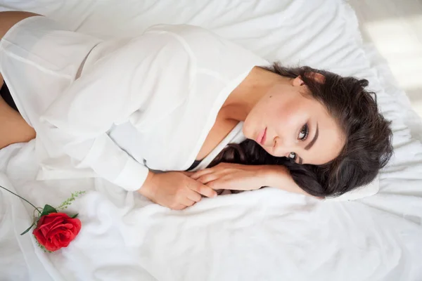 Ragazza in lingerie sdraiata su un letto con una rosa — Foto Stock