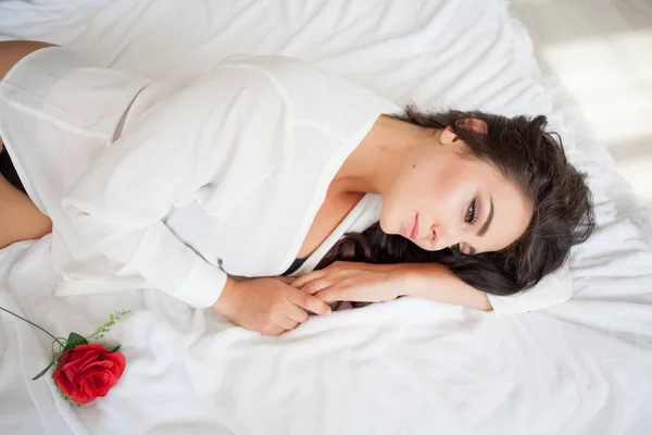 Chica en lencería acostada en una cama con una rosa — Foto de Stock