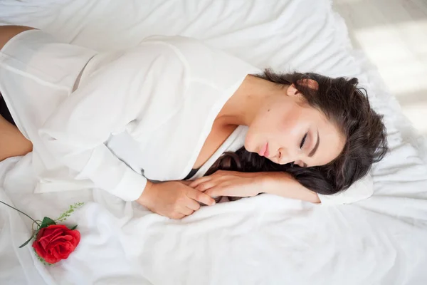 Chica en lencería acostada en una cama con una rosa —  Fotos de Stock