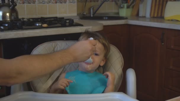 Little boy μπαμπά τροφοδοτεί το χυλό στην κουζίνα — Αρχείο Βίντεο