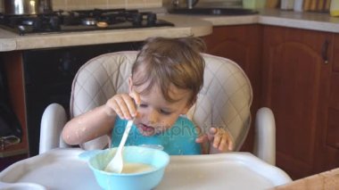 küçük çocuk yulaf lapası kahvaltıda yiyor.