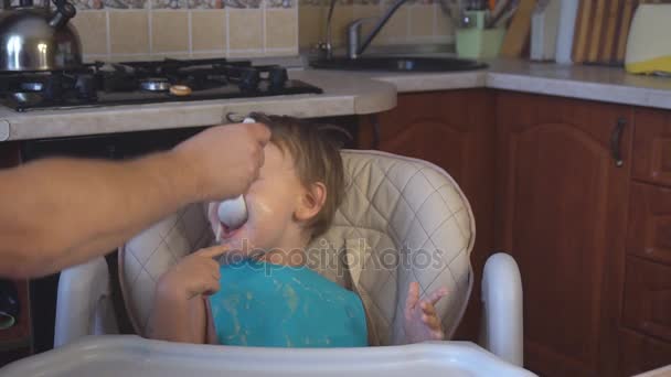 Pequeno menino pai alimenta o mingau de cereal na cozinha — Vídeo de Stock