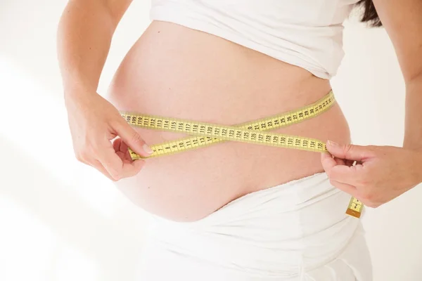 The stomach of a pregnant woman and a measuring tape — Stock Photo, Image
