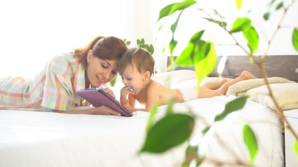 Anne ve genç oğlu yatak odasında internet tablet zevk — Stok video