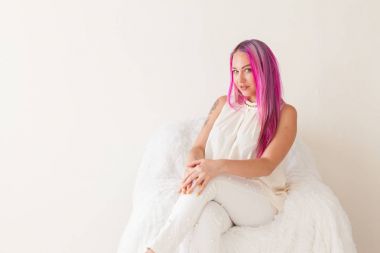 pembe saçlı kız beyaz oda bir sandalyede oturuyor