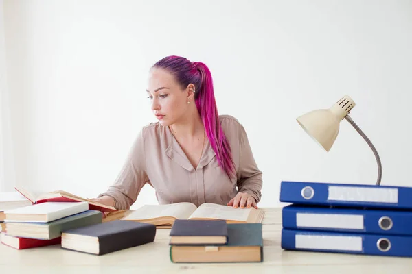 Mujer de negocios con el pelo rosa se sienta en la oficina lee libros de educación — Foto de Stock