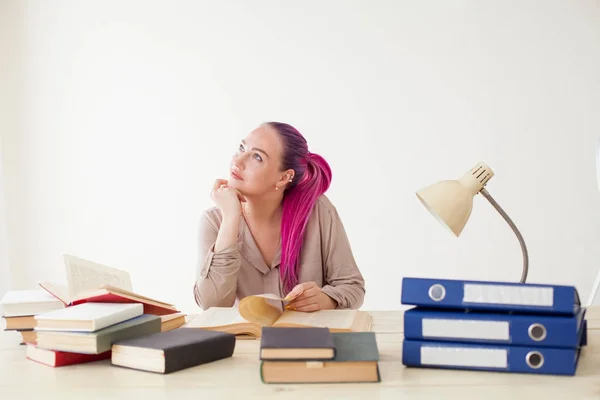 Mujer de negocios con el pelo rosa se sienta en la oficina lee libros de educación — Foto de Stock
