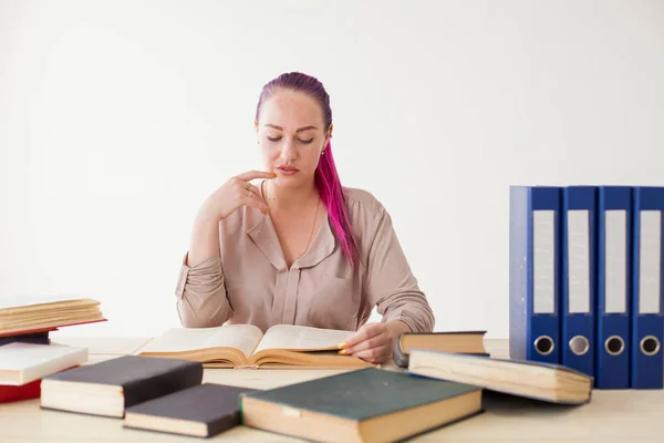 Mujer de negocios con el pelo rosa se sienta en la oficina lee libros de educación — Foto de Stock