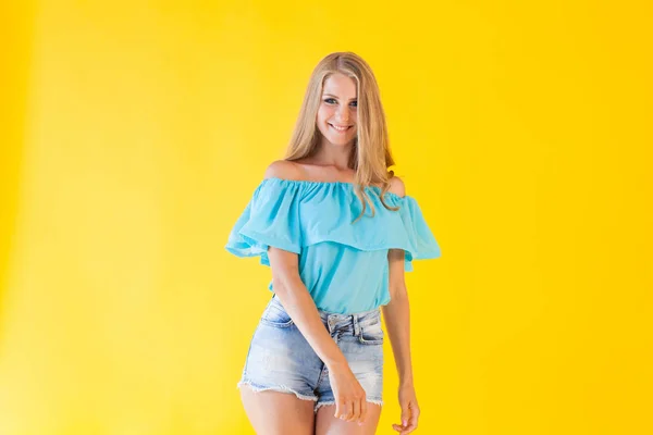 Красивая блондинка с голубыми шортами на желтом фоне — стоковое фото