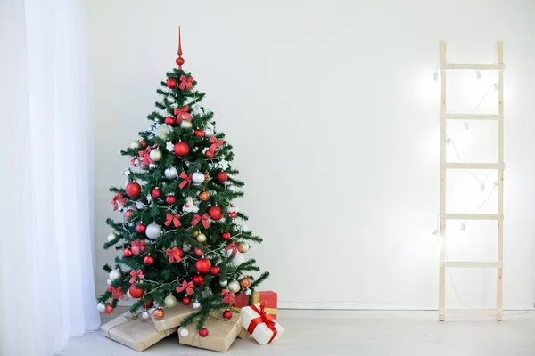 Árbol de Navidad en una habitación blanca con regalos de felicitación navideños —  Fotos de Stock