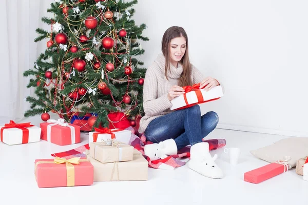 Девушка смотрит рождественские подарки на елку — стоковое фото