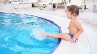 küçük oğlan poolside resort adlı oturuyor