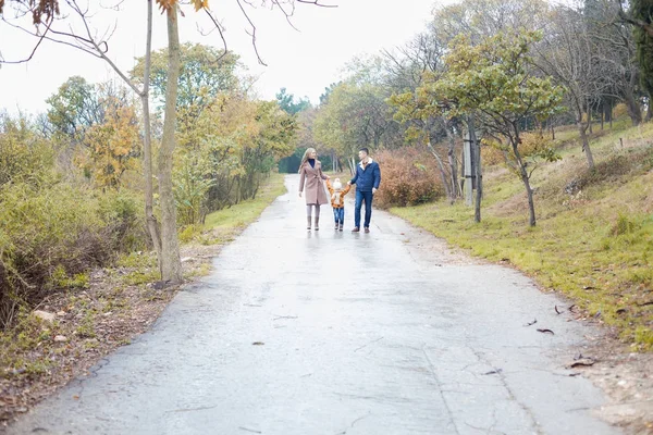 Uma família com um filho ir na estrada na chuva — Fotografia de Stock