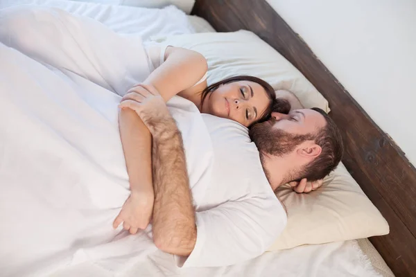 Un hombre y una mujer durmiendo en un dormitorio en una cama blanca — Foto de Stock