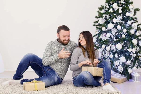 En kille med en tjej öppna presenter jul nyår — Stockfoto