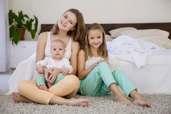 Tres hermanas juegan a los niños por la mañana en el dormitorio — Foto de Stock