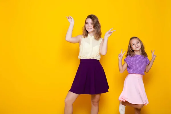 两个女孩在彩色礼服笑显示手指 — 图库照片