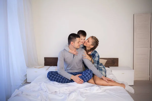 Mamá papá e hijo por la mañana acostados en la cama en casa de buen humor — Foto de Stock