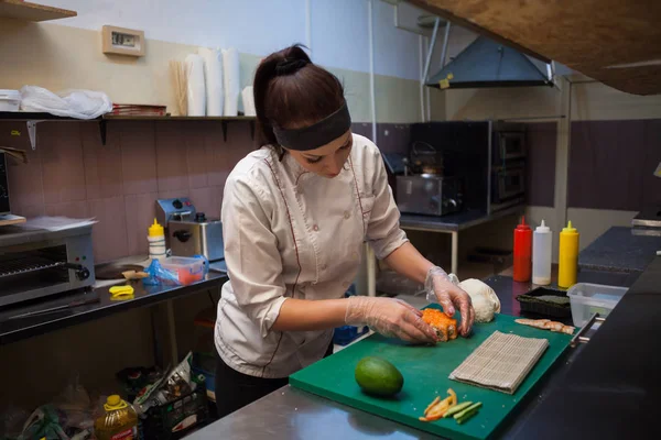 woman Cook prepares food sushi kitchen