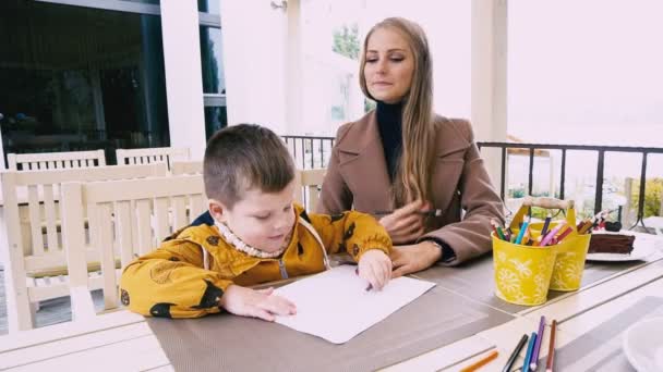 Mamá e hijo pequeño pintan en un restaurante — Vídeos de Stock