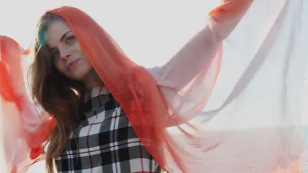 Красивая женщина с красной шалью дует на ветру — стоковое видео