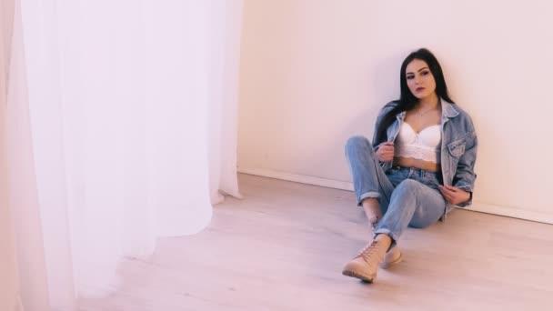 Bruna ragazza in jeans vestito seduto sul pavimento — Video Stock