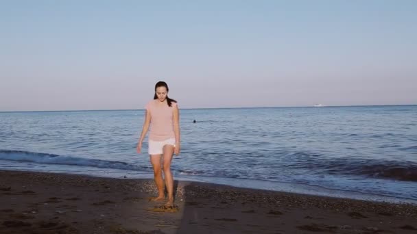 Bonita chica haciendo ejercicios matutinos en la playa junto al mar — Vídeos de Stock