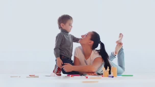 Madre e figlio giocare disegnare ride in una stanza bianca — Video Stock