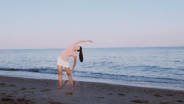 Vacker flicka gör morgon övningar på stranden vid havet — Stockvideo